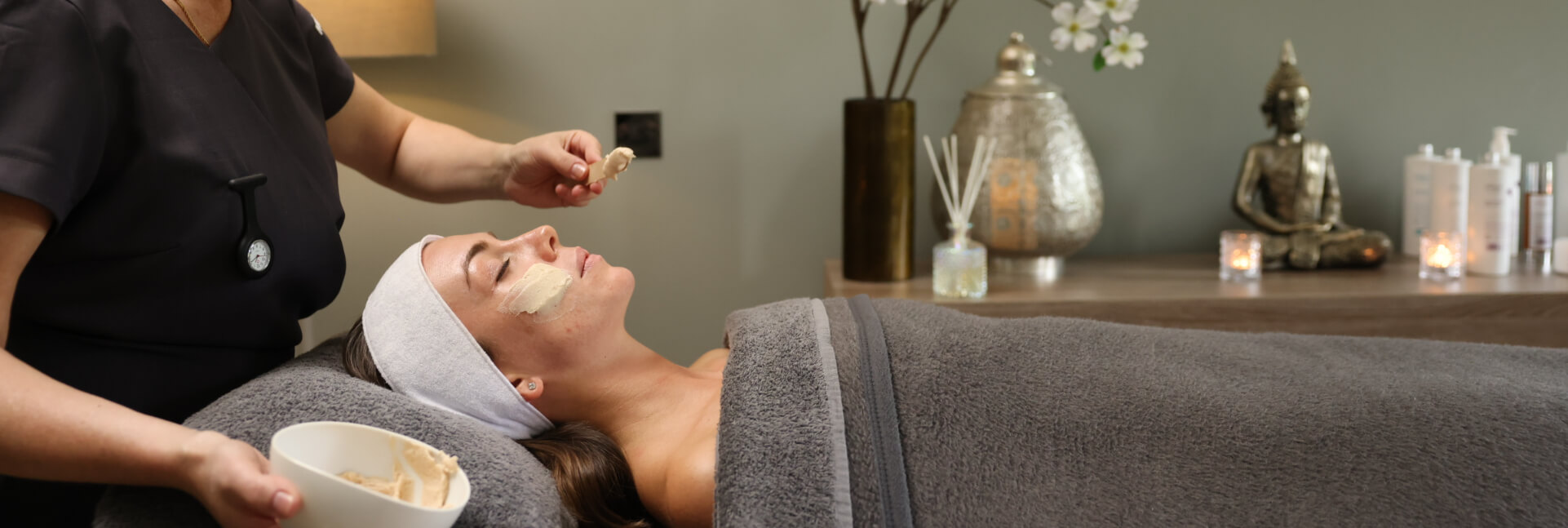 A therapist applying a facial mask to a relaxed guest in a serene spa setting at a JA Resorts & Hotels property