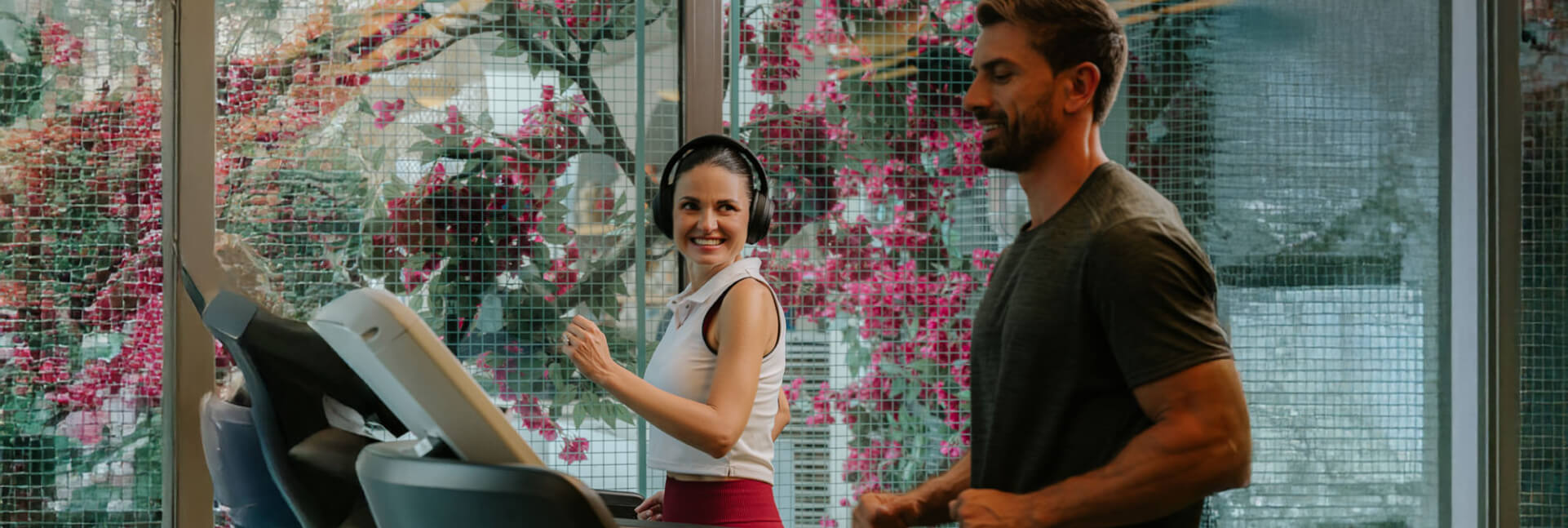 A smiling woman and a man exercising on a treadmill at JA Ocean View Hotel Dubai